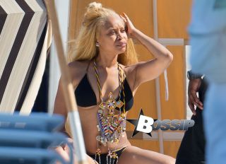Erykah Badu shows off her incredible bikini body while on vacation in Miami. The 42-year-old music legend wore a large African tribal necklace over a black bikini as she soaked up the sun with a mystery hunk who was spotted fetching her food and drinks.