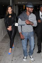 Taye Diggs leaves 1 Oak nightclub with a mystery woman. Taye is looking stylish in a gray shirt blue jeans and a blue hat while his date wears all black, black jacket with matching black skinny pants with bright blue heels.