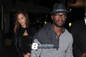 Taye Diggs leaves 1 Oak nightclub with a mystery woman. Taye is looking stylish in a gray shirt blue jeans and a blue hat while his date wears all black, black jacket with matching black skinny pants with bright blue heels.