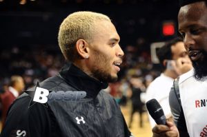 Rihanna watches her ex boyfriend Chris Brown as he plays a charity basketball while she sits courtside with Cara Delevingne. The girls were talking as Chris played ball and Chris did not look over at her but Rihanna looked at him many times as he went up and down the court. Later she was seen smiling as she posed with many children and even hugged as they came up to greet her
