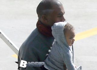 **USA ONLY** Sydney, Australia - Kanye West, his daughter North and wife Kim Kardashian disembark off of a plane at Sydney Airport. Kim looked classy for her travels in a partially buttoned white blouse and a fitted black pencil skirt. Security kept a tight watch as Kanye carried his adorable 1-year-old to their awaiting car on the airport tarmac. The internationally famous family is in town for Kanye's next Yeezus tour stop.
