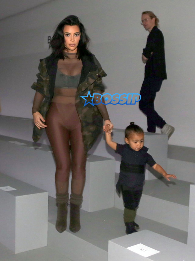 Kim Kardashian wears a sheer body suit designed by Kanye with baby North West at his fashion show NYC