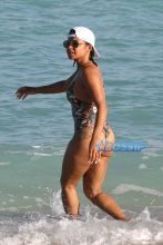AKM-GSI Christina MIlian wears floral pineapple black thong one-piece and baseball cap for Miami Beach day with daughter Violet