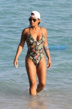 AKM-GSI Christina MIlian wears floral pineapple black thong one-piece and baseball cap for Miami Beach day with daughter Violet