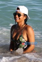 AKM-GSI Christina MIlian wears floral pineapple black thong one-piece and baseball cap for Miami Beach day with daughter Violet