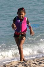 AKM-GSI Christina MIlian wears floral pineapple black thong one-piece and baseball cap for Miami Beach day with daughter Violet