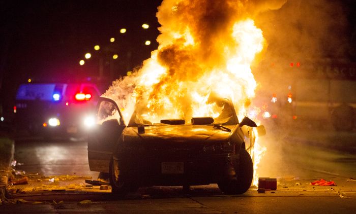 A car burns as a crowd of more than 100 people gathers following the fatal shooting of a man in Milwaukee, Saturday, Aug. 13, 2016. The Milwaukee Journal Sentinel reported that officers got in their cars to leave at one point, and some in the crowd started smashing a squad car's window, and another vehicle, pictured, was set on fire. The gathering occurred in the neighborhood where a Milwaukee officer shot and killed a man police say was armed hours earlier during a foot chase. (Calvin Mattheis/Milwaukee Journal-Sentinel via AP)