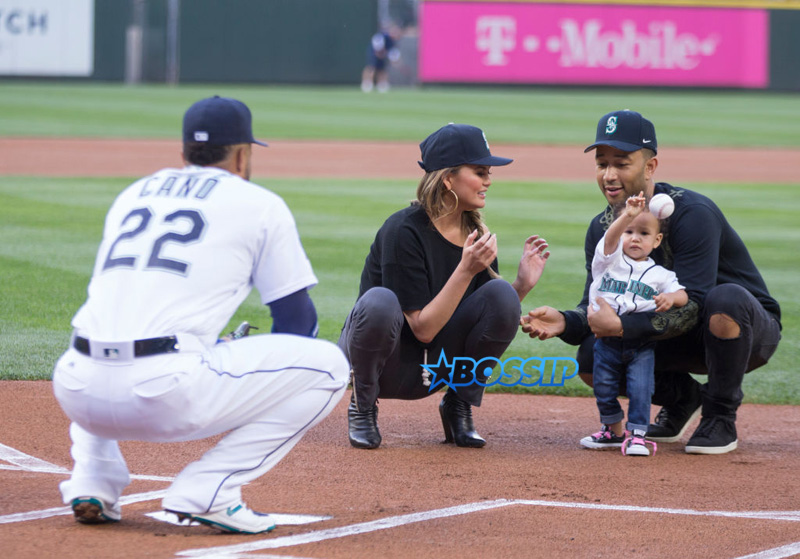 SEATTLE, WA - JUNE 6: With the help of mother Chrissy Teigen, center, and father John Legend, Luna Stephens throws out the ceremonial first pitch to Robinson Cano #22 of the Seattle Mariners before a game between the Minnesota Twins and the Seattle Mariners at Safeco Field on June 6, 2017 in Seattle, Washington. (Photo by Stephen Brashear/Getty Images)