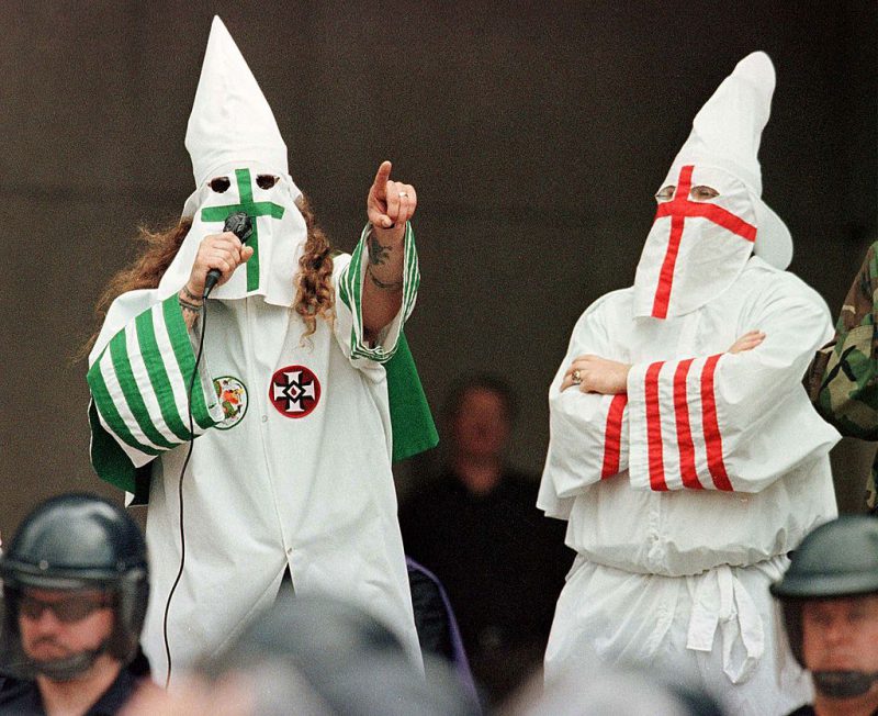 CLEVELAND, : The Grand Dragon of the Michigan Ku Klux Klan (L) addresses the crowd as another Klan member looks on during a KKK rally 21 August, 1999, in downtown Cleveland, Ohio, as part of the KKK's effort to spread their message of segregation, hate and intolerance toward black gays aand Jews. Although the rally coincided with the start of the city's annual Black Family Reunion and the Cleveland Brown's first home game, the meeting, in front of a crowd of fewer than 300, remained calm with no arrests or disruptions.