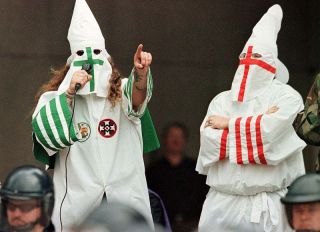 CLEVELAND, : The Grand Dragon of the Michigan Ku Klux Klan (L) addresses the crowd as another Klan member looks on during a KKK rally 21 August, 1999, in downtown Cleveland, Ohio, as part of the KKK's effort to spread their message of segregation, hate and intolerance toward black gays aand Jews. Although the rally coincided with the start of the city's annual Black Family Reunion and the Cleveland Brown's first home game, the meeting, in front of a crowd of fewer than 300, remained calm with no arrests or disruptions.