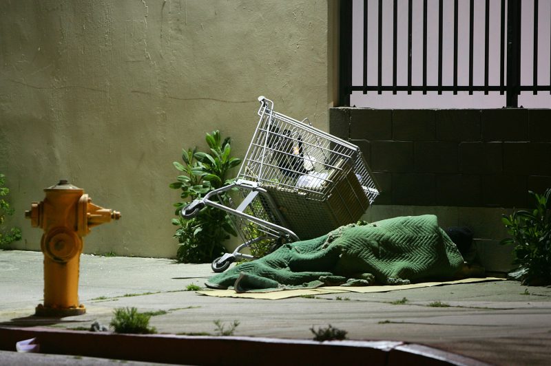 LOS ANGELES, CA - APRIL 19: A homeless person sleeps by his shopping cart on a downtown sidewalk in the early morning hours of April 19, 2006 in Los Angeles, California. Most homeless tents and improvised shelters are taken down at dawn, before their possessions can be hauled away by cleaning crews. A 9th U.S. Circuit Court of Appeals panel ruled last week that a city law making it illegal to sleep or sit on city sidewalks cannot be implemented as long as there is a shortage of homeless shelter beds in Los Angeles. According to a study released in January by the Los Angeles Housing Services Authority, there are nearly 90,000 homeless people live in Los Angeles County but only 9,000 to 10,000 beds available in homeless shelters, single-room occupancy hotels, and other facilities