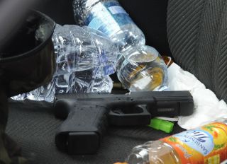 This photo taken on February 3, 2018 shows a Glock handgun sitting on the seat of a black Alfa Romeo used by a man suspected of wounding several foreign nationals in a drive-by shooting in Macerata. Italian police said they have arrested a man suspected of opening fire on foreigners from a vehicle in central Italy on February 3. Media reported six people were injured, four of them seriously, in the incident in the town of Macerata.