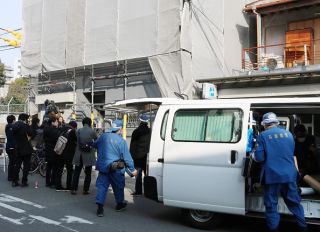 Hyogo prefectural police (R) are pictured at the scene as they investigate an apartment (L) where a decapitated head was found in Osaka on February 25, 2018. Japanese police are questioning a US man in custody after a decapitated head was found in an Osaka apartment he was renting, local media reported on February 25.