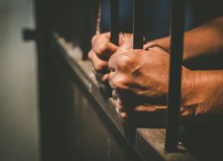 Man Holding Prison Bars