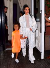 Kim Kardashian NYC Hotel with daughter North West on Saturday night. They headed to NBC Studios to watch Dad, Kanye West, perform on SNL. North wore a custom Yeezy dress in Neon Orange, while Kim wore a white python trench coat and matching pants combo.
