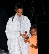 Kim Kardashian NYC Hotel with daughter North West on Saturday night. They headed to NBC Studios to watch Dad, Kanye West, perform on SNL. North wore a custom Yeezy dress in Neon Orange, while Kim wore a white python trench coat and matching pants combo.