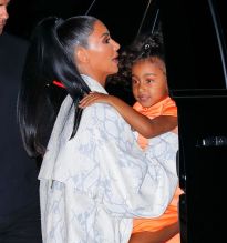 Kim Kardashian NYC Hotel with daughter North West on Saturday night. They headed to NBC Studios to watch Dad, Kanye West, perform on SNL. North wore a custom Yeezy dress in Neon Orange, while Kim wore a white python trench coat and matching pants combo.