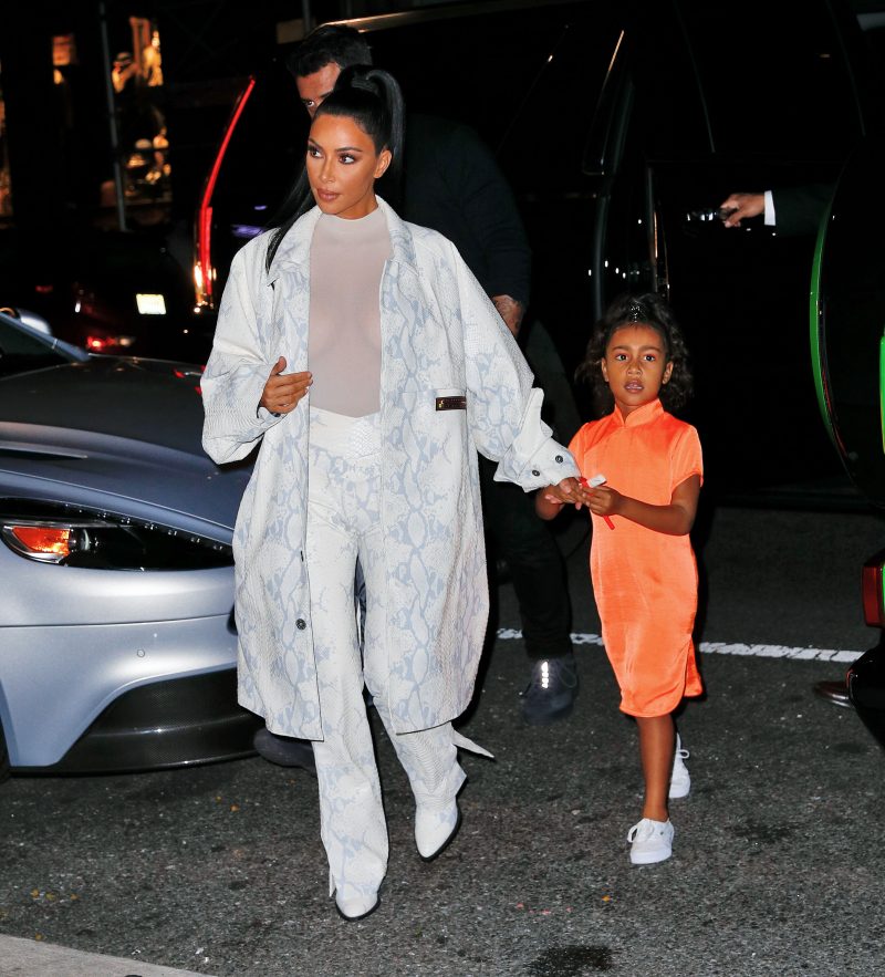 Kim Kardashian NYC Hotel with daughter North West on Saturday night. They headed to NBC Studios to watch Dad, Kanye West, perform on SNL. North wore a custom Yeezy dress in Neon Orange, while Kim wore a white python trench coat and matching pants combo.