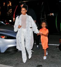 Kim Kardashian NYC Hotel with daughter North West on Saturday night. They headed to NBC Studios to watch Dad, Kanye West, perform on SNL. North wore a custom Yeezy dress in Neon Orange, while Kim wore a white python trench coat and matching pants combo.