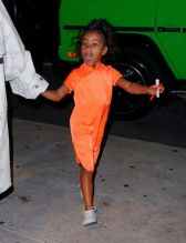 Kim Kardashian NYC Hotel with daughter North West on Saturday night. They headed to NBC Studios to watch Dad, Kanye West, perform on SNL. North wore a custom Yeezy dress in Neon Orange, while Kim wore a white python trench coat and matching pants combo.
