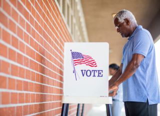A senior black man casts his ballot on election day.