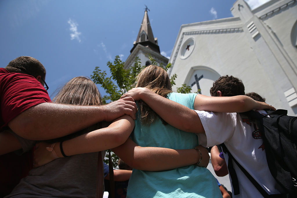 CHARLESTON, SC - JULY 17:  A church youth group from Douthan, Alabama prays in front of the Emanuel AME Church on the one-month anniversary of the mass shooting on July 17, 2015 in Charleston, South Carolina. Visitors from around the nation continue to pay their respects at a makeshift shrine in front of the church, in a show of faith and solidarity with 