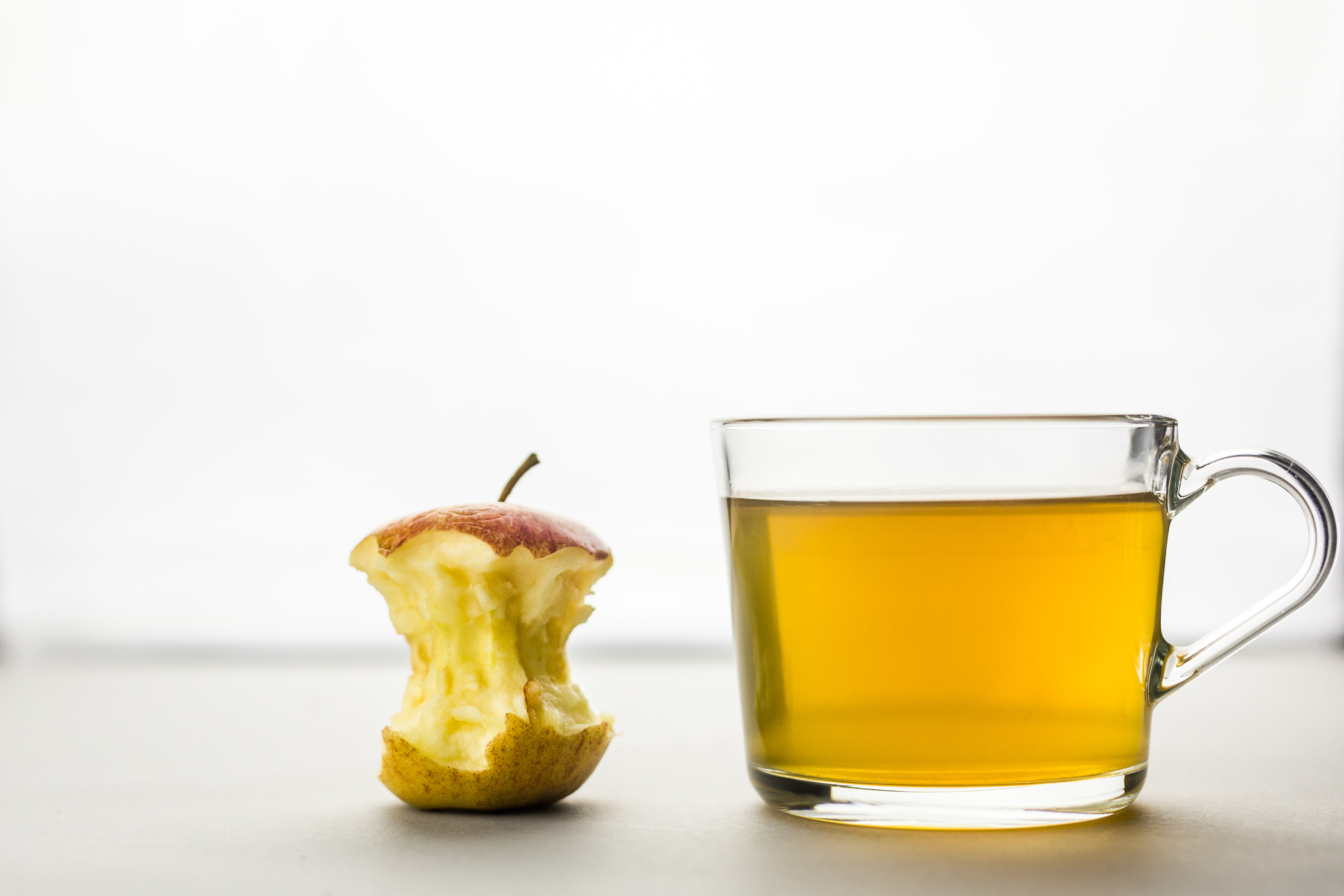 Close-Up Of Drink And Apple Core Against White Background