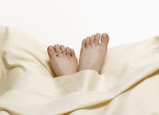 Woman?s feet on pillow in bed