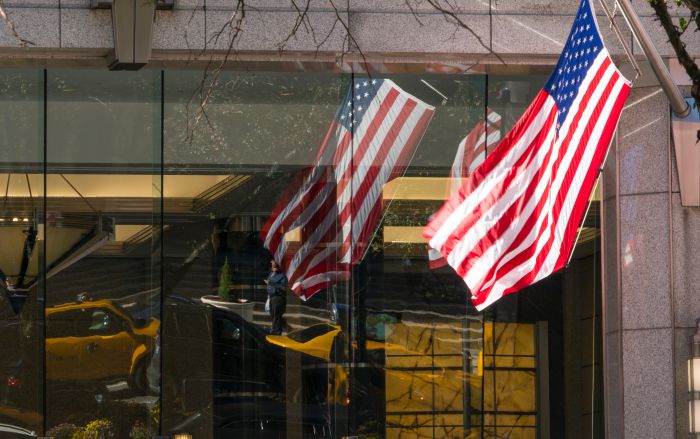 Yellow taxis and pedestrians reflect to the building windows behind the shaking American flags at Midtown Manhattan NY USA on Nov. 08 2018.