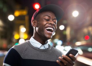 Man laughing at phone in urban street at night