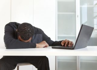 Tired Black businessman sleeping near laptop
