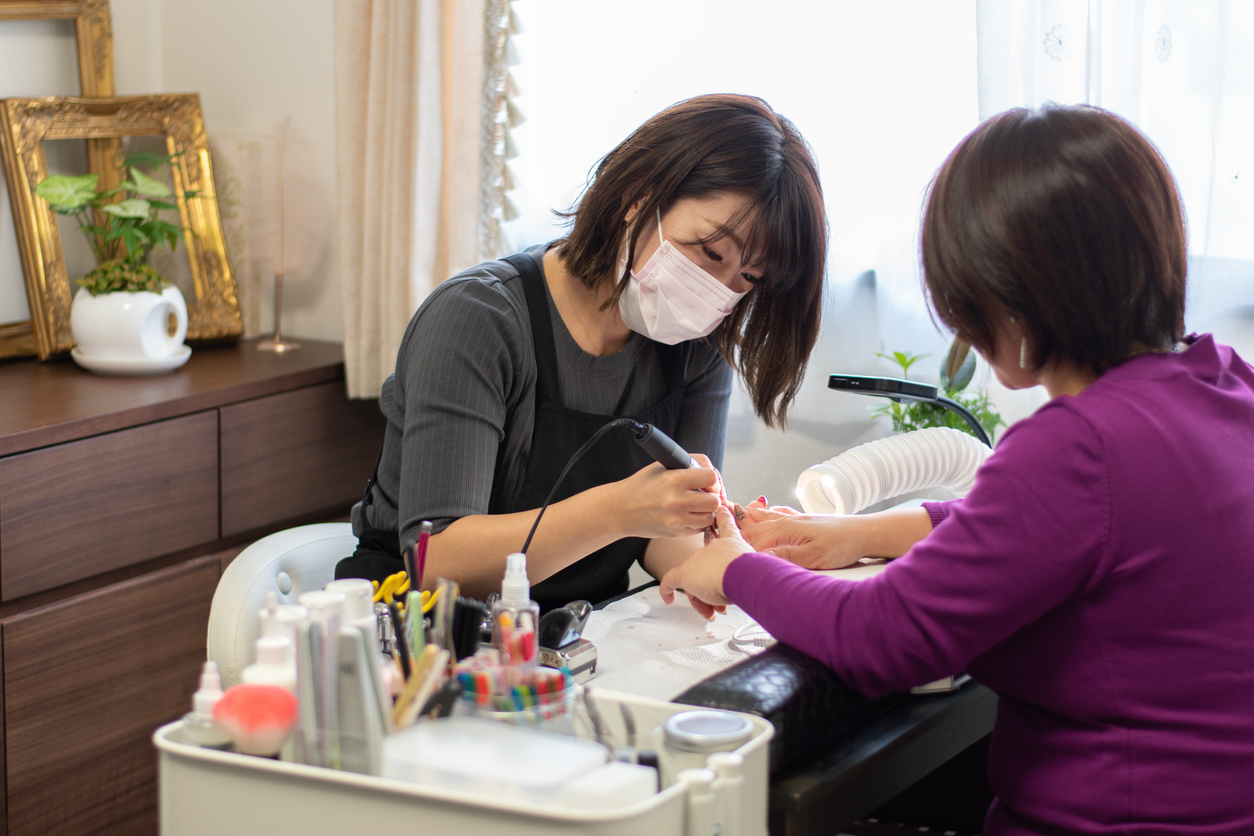 Candid Side Shot of Japanese Nail Salon Owner Filing Customer Nails