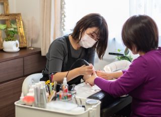 Candid Side Shot of Japanese Nail Salon Owner Filing Customer Nails