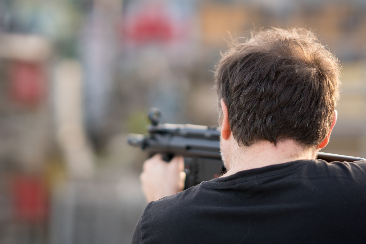 Rear View Of Man Shooting Gun Outdoors