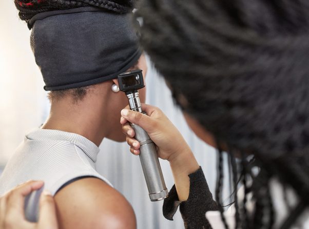 Doctor examining woman's ear with otoscope