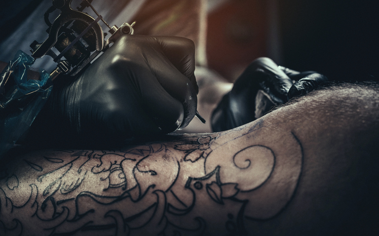 Tattoo master making tattoo on leg