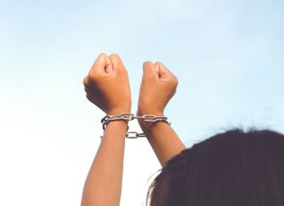 Low Angle View Of Woman Hands With Chain Against Clear Sky