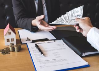 Cropped Hand Giving Money To Businessman At Desk In Office