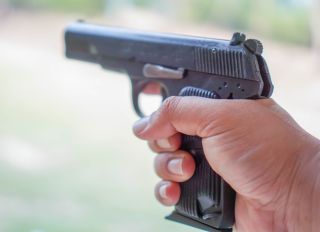 Cropped Image Of Hand Holding Gun