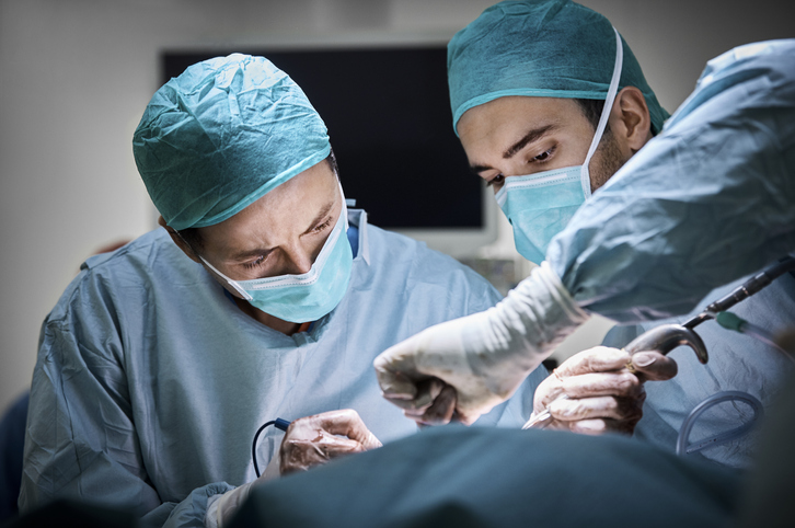 Doctors using equipment while operating patient