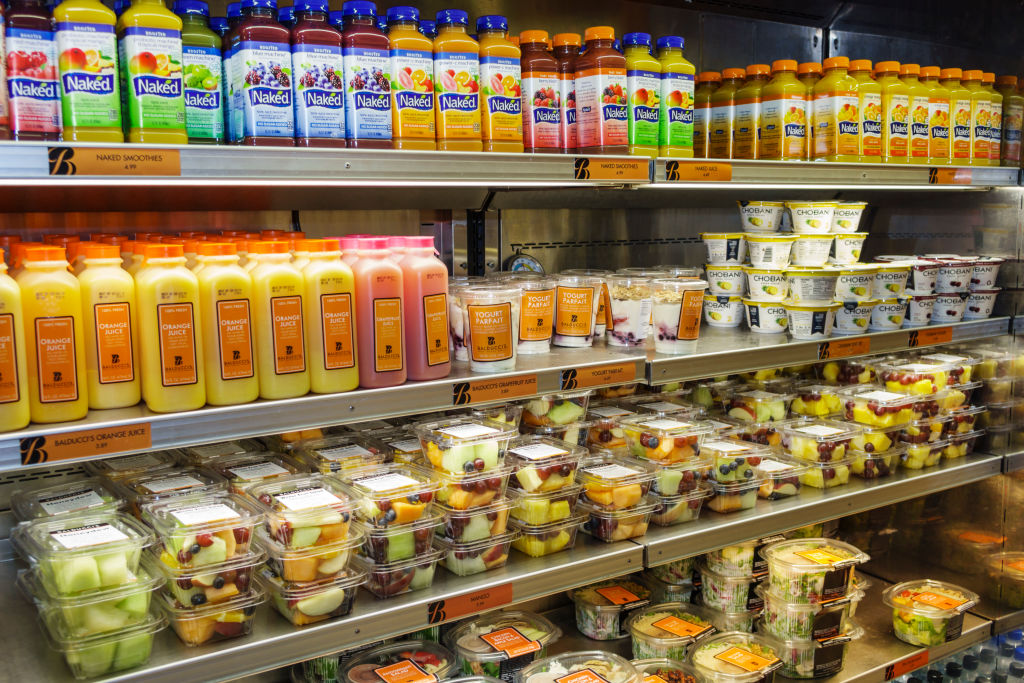 A refrigerated display case of fruit and drinks at John F. Kennedy International Airport.