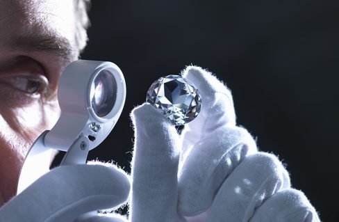 Jeweller inspecting replica diamonds with loupe