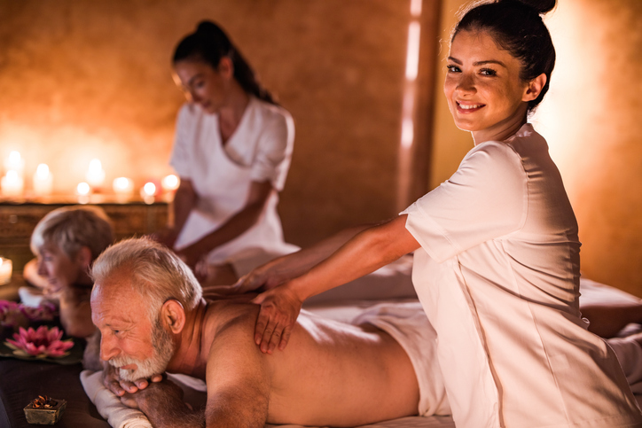 Happy female therapists massaging mature couple at the spa.