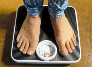 Woman weighing herself on scales.