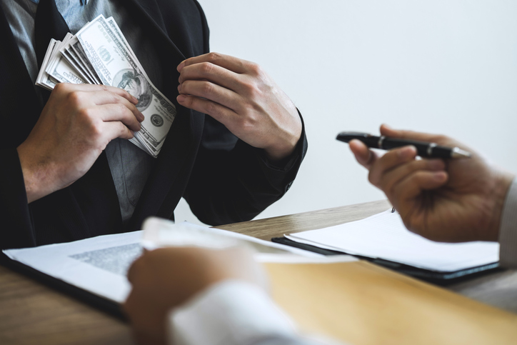 Midsection Of Man Offering Bribe To Agent