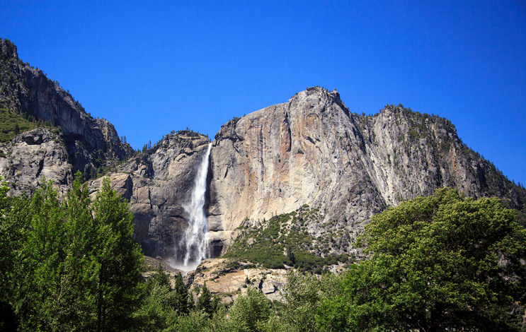 Low Angle View Of Waterfall Against Clear Blue Sky