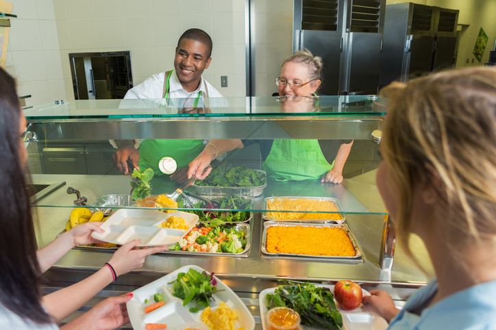 Diverse cafeteria works serve high school students