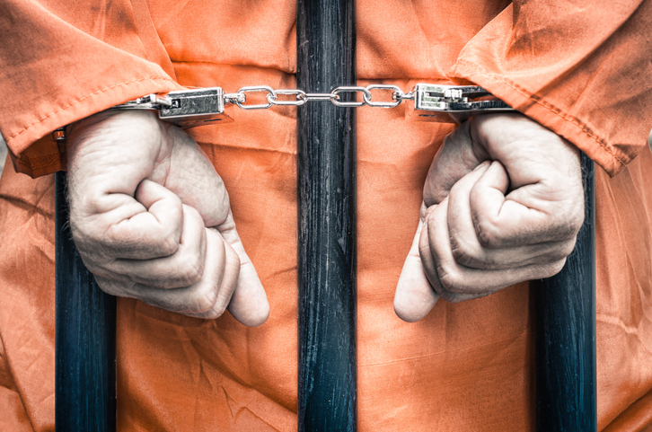 Close-Up Of Man With Handcuffs Standing In Prison