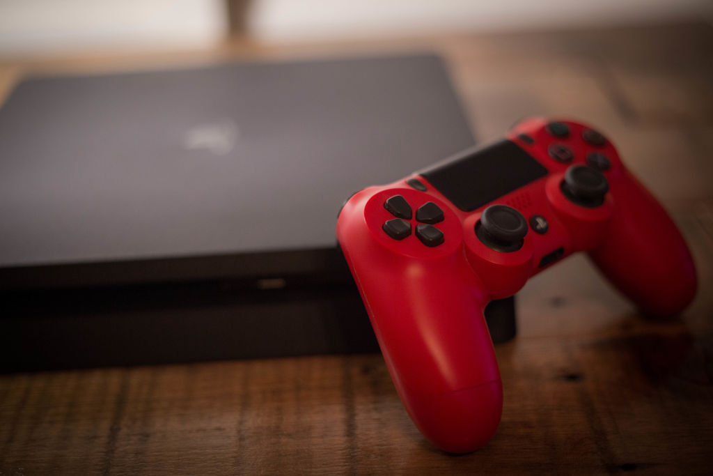 A Sony PlayStation 4 video game console with a red wireless...