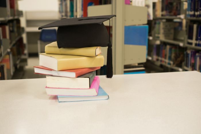 Stack Of Books And Mortarboard On Table